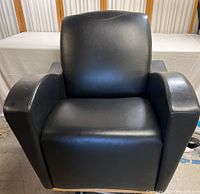 Front view of the black leather club chair showing seat, backrest, and armrests.
