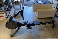 Front-left angled view of entire rowing machine showing frame, seat, rail, and resistance housing