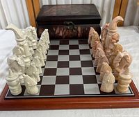 Chess set arranged on wooden chessboard with storage box in background, showing whole set and layout.