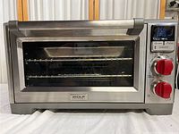 Front view of stainless steel countertop convection oven with glass door and red knobs