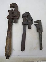 Three heavy duty pipe wrenches of different sizes shown upright on white background