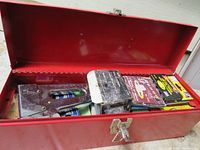 Red metal toolbox opened showing staple gun and several boxes of new staples.