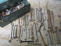 Metal tool box open with 37 assorted wrenches laid in front, showing different sizes and types including combination and open-end wrenches.