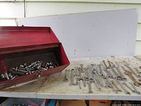 Red metal tool box open with assorted sockets inside. 41 wrenches including ratchets arranged on the surface next to the tool box.
