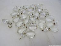 Cluster of vintage glass prisms showing teardrop shapes with faceted surfaces and brass wire loops for hanging.