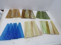 All 32 vintage slag lamp glass panels laid out grouped by color and size: caramel brown, brownish marbled, green, light cream, cobalt blue textured.