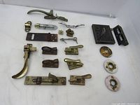 Complete view of all vintage window lock components including metal and brass locks, handles, latches, and porcelain escutcheon plates arranged on white background.