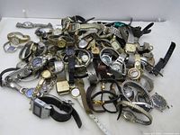 Top view of a mixed lot of wrist watches showing various styles and bands piled together