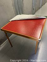 Photo showing the red tabletop with wooden edges and foldable wooden legs visible.