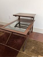 Side angled view of rectangular wood end table with glass inset on lower shelf and solid wood top shelf.