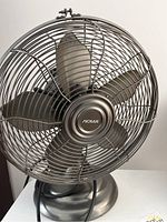 Front view of Noma 12-inch table top fan with metal blades and grill.