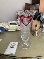 Front view of the Hoffbauer Collection lead crystal vase showing the cranberry cut heart-shaped design with floral engraving on the body.