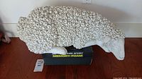 Side view of white lamb sculpture showing curly wool texture and overall length