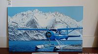 Full view of blue seaplane print with snow-covered mountains in background
