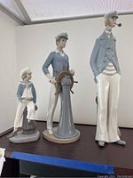 Full set of three Lladro porcelain sailor statues together on a shelf.