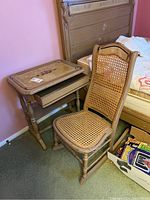 View of table with drawer partially pulled out and matching rocker chair with cane seating and backrest, showing both items and condition.