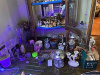 Wide view of lot on floor with vases, flower frogs, oil lamps, planters, and other decorative items.