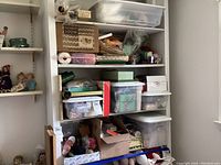 Shelf unit with four shelves filled with various boxes, plastic bins, and bags containing assorted craft supplies including yarn and tools.