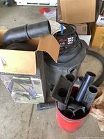 Whole vac with hose attachments laid around and inside a cardboard box