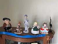 Six figurines in one photo arranged on a shelf showing all ceramic characters and the wood crane.