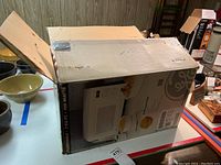 Closed original box of GE Microwave Oven Model JES735WD002 with visible branding and product image.