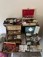 Overview of four open jewelry boxes and cases on a table showing various small jewelry items