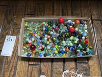 Top-down image showing a full box of assorted glass marbles and pebbles in various colors and sizes.