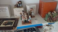 Five Norman Rockwell collectible figures displayed with original boxes and some unopened packaging, showing detailed characters and scenes inspired by the artist's works.