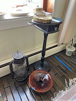Photo showing the ceramic spittoon, vintage lantern, and wooden smoke stand grouped together on the floor.