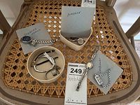 Four wristwatches displayed on chair seat including Diamond brand, Armitron, and two unbranded watches with a small container holding extra watch band pieces.