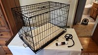 Full wire dog crate on table, showing size and padding inside.