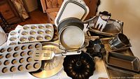 Overview of baking pans including muffin tins, round cake pans, bundt pans, sifters, and some kitchen utensils.
