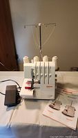 Front view of Bernina 800DL serger with four spools and manual at right