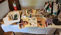 Overview of the lot showing assorted paint brushes, instruction books, magazines, paints, painted rocks, and floral tote.