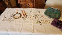 Full assortment of costume jewelry items and two purses laid on table