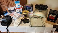Complete set of assorted fun gadgets displayed on a table, featuring the weight scale, fondue set, sound machine, 3D printer, and others.