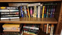 Top wooden shelf with hardback John Grisham novels and other assorted paperbacks.