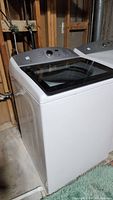 View of Kenmore top load washing machine with glass lid from an angle, showing white exterior and grey control panel.
