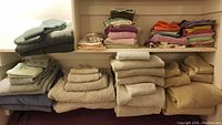 Full view of two shelves with various stacked towels in multiple colors and sizes.