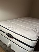 Close-up view of mattress side showing Beautyrest tag and tilted positioning against wall.