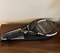 Two tennis racquets stacked on their cases, showing the Prince Triple Threat racquet on top.