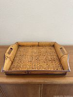 Full view of the large rectangular woven bamboo serving tray showing the woven base and bamboo sides with integrated handles.