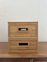 Front view of two stacked bamboo storage containers showing cut-out handles and smooth bamboo surfaces.