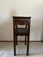 Front and partial side view of the vintage rosewood tea table showing its carved apron, leg structure, and lower shelf.