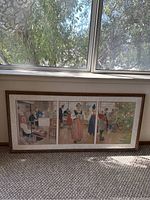 Full view of framed triptych leaning against wall under window showing three panels and frame