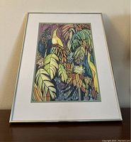 Frontal view of the framed "Jungle Family" art print showing colorful tropical leaves, birds, and floral pattern within a silver metal frame and white matting.