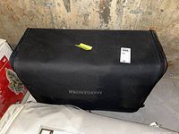 Black Frountgate branded soft luggage bag on basement floor, showing front logo and shape.