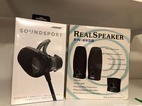 Front of Bose SoundSport earbuds box and Real Speaker RW-695B speakers box side by side.