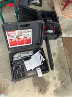 Overview photo showing the Porter Cable Profile Sander in carrying case with manual and sanding accessories along with a chainsaw in its case.