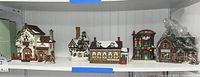 Wide shelf view with six ceramic Christmas village buildings arranged in a row